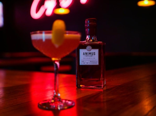 A cocktail next to a bottle of Ananas Gin