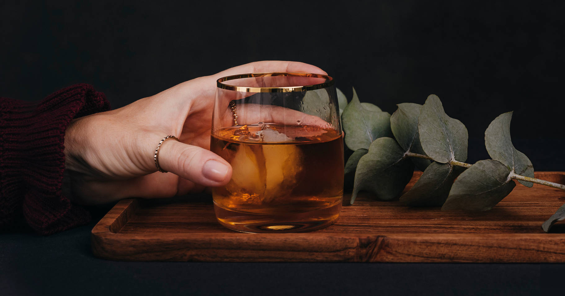 A hand holding a whisky glass